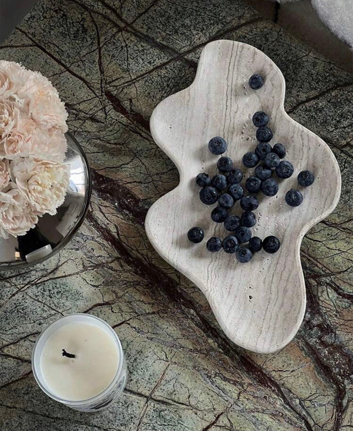 A travertine platter styled with a fluted pillar candle
