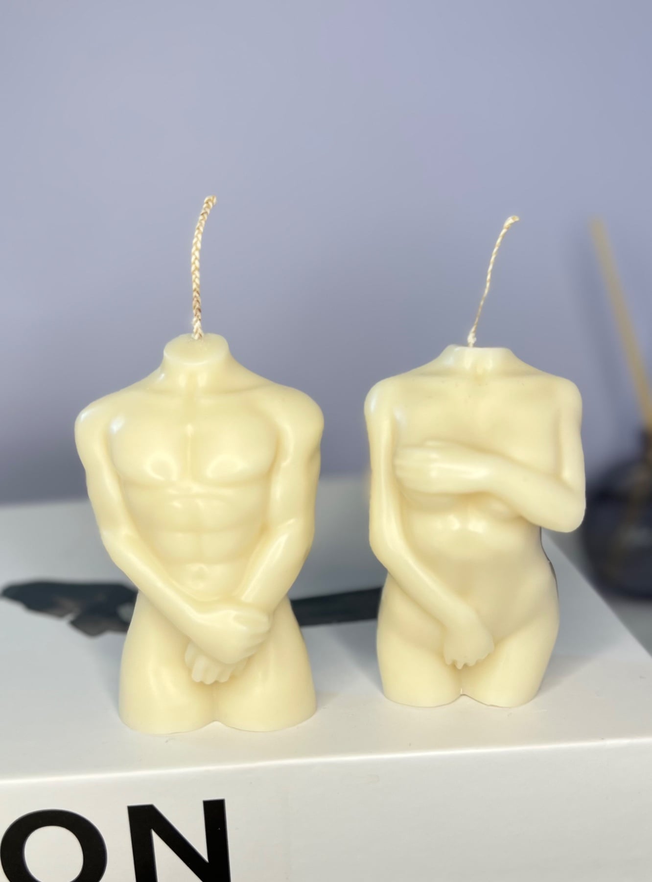 A pair of body-torso candles, his and hers, hand-poured in soy wax