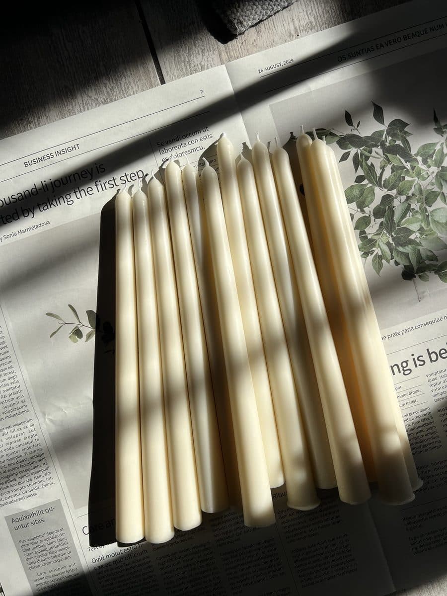 Cream dinner taper candles, hand-poured, laid out on paper