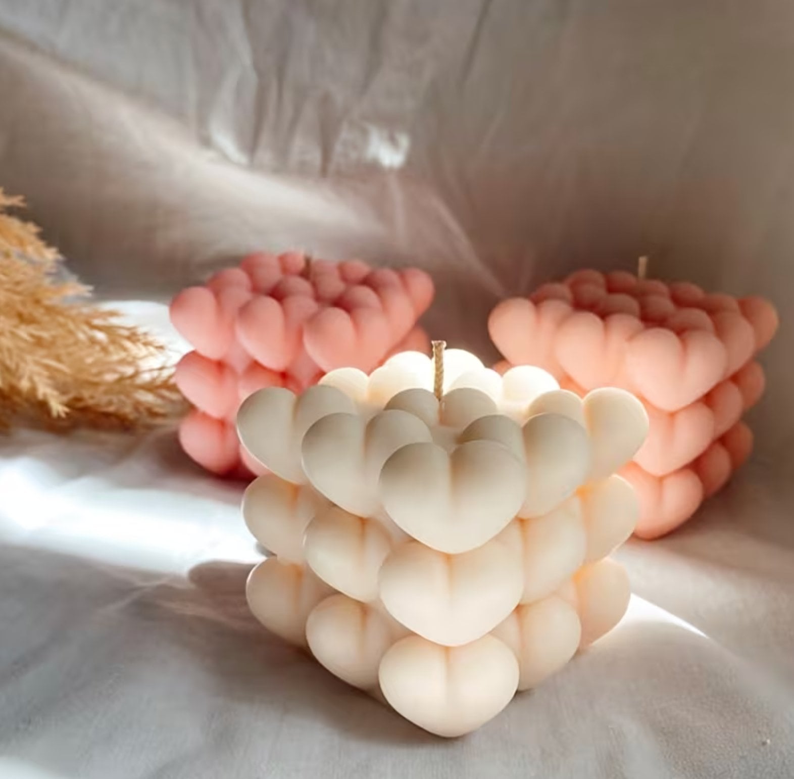 A cube of clustered heart shapes, lit, hand-poured in soy wax